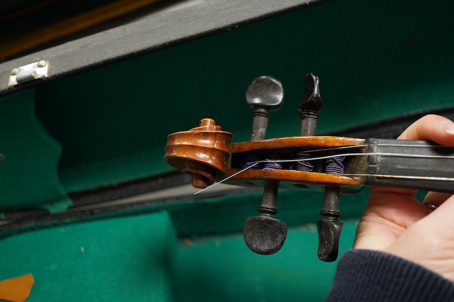 Four cased violins; an early 20th century violin, body 36cm, fitted with a microphone pick up taking a quarter inch jack plug, an early 20th century half size violin, body 32cm, and two student violins. Condition - poor